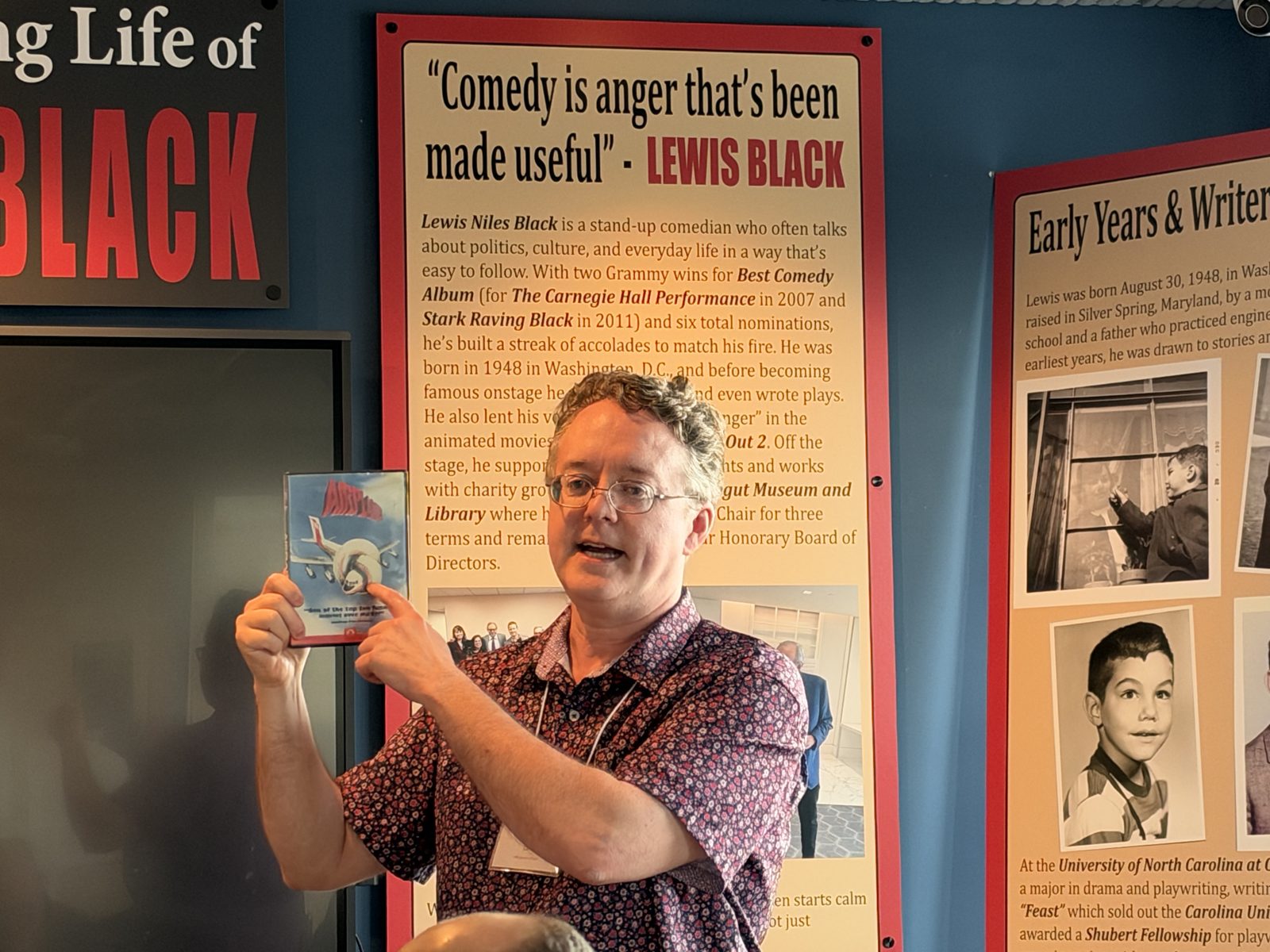 A presenter holds up a book while speaking at the Kurt Vonnegut Museum and Library